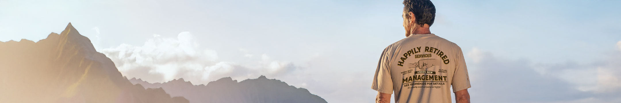 Person wearing a shirt with text standing in front of mountainous landscape