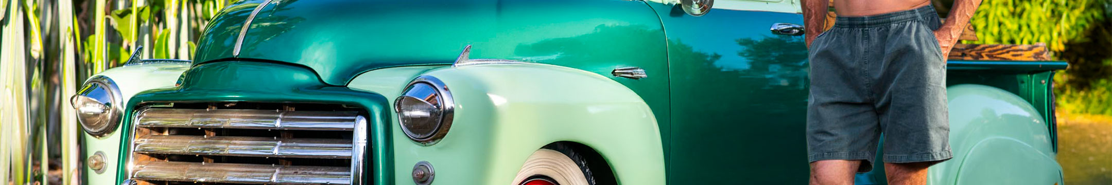 Person standing next to a vintage green truck with a blurred natural background
