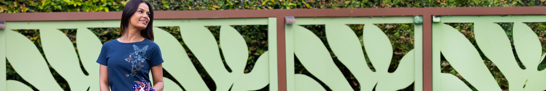 Woman standing in front of a decorative metal fence with leaf patterns