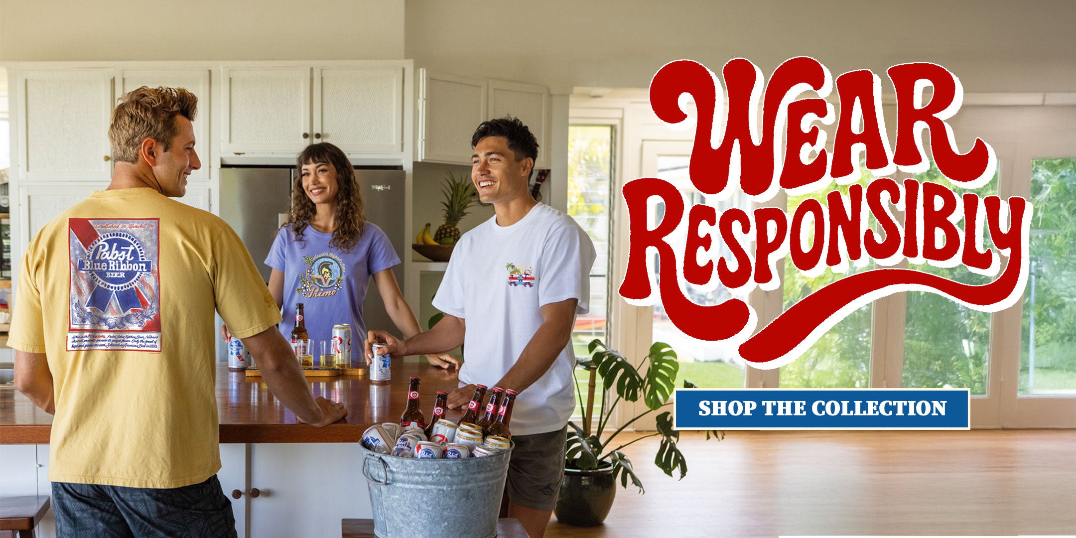 Three people in a kitchen with a 'Wear Responsibly' sign and a bucket of beer.