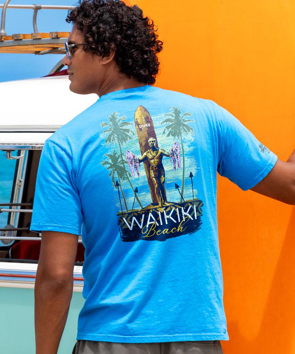 A person wearing a blue crewneck t-shirt with a statue print and the text 'Waikiki Beach' on the front. View 2