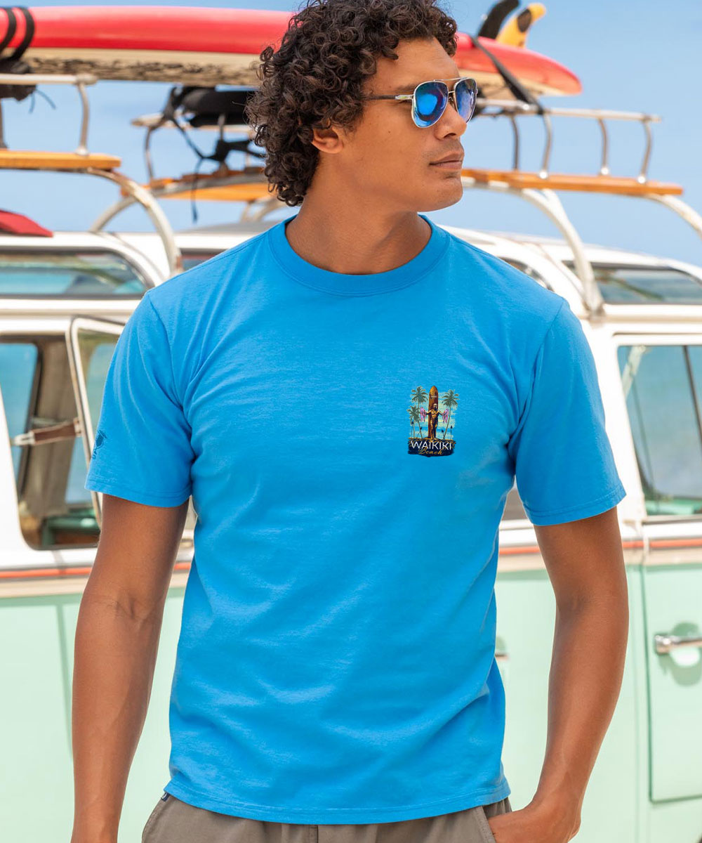 Man wearing a blue shirt with a small logo on it standing in front of a vintage car View 3