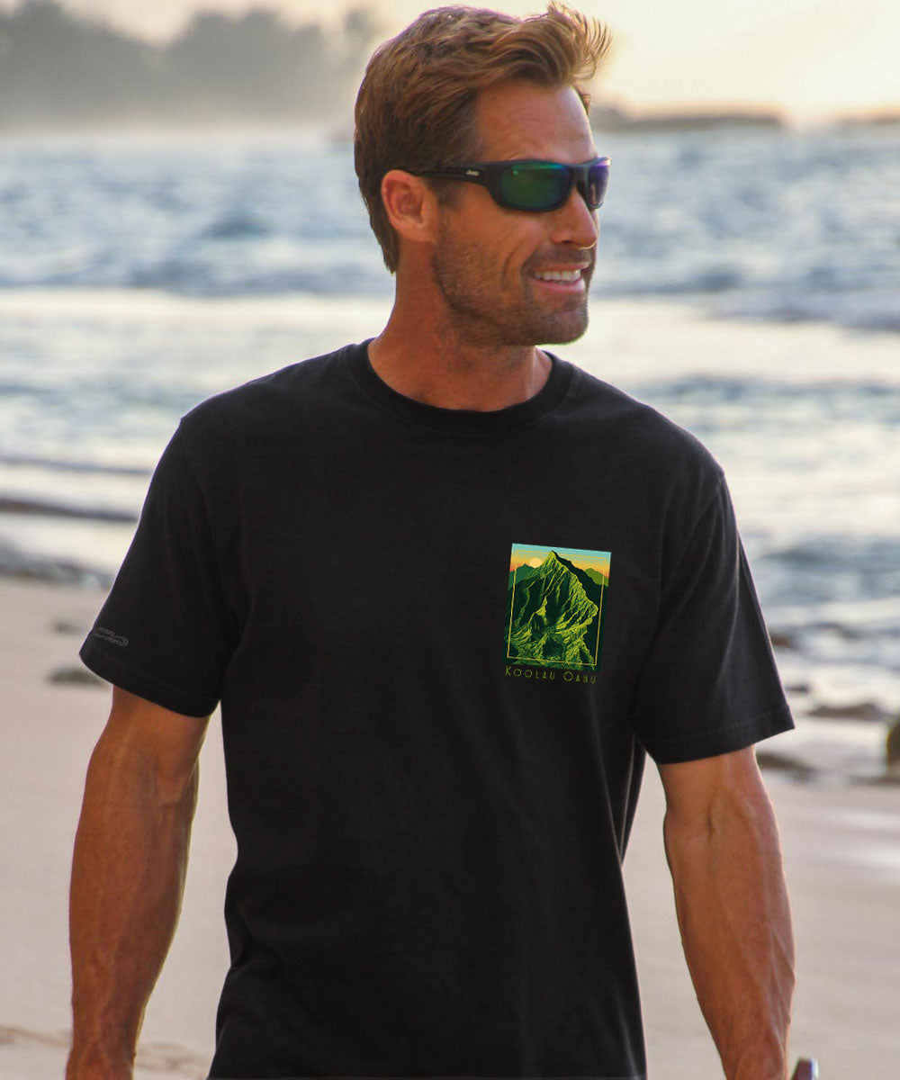 Man wearing a black t-shirt with a small green graphic on the chest. View 3