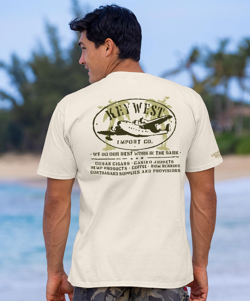 Man at the beach wearing a short sleeve white t-shirt with 'Key West Import Co.' logo and text on the back View 2