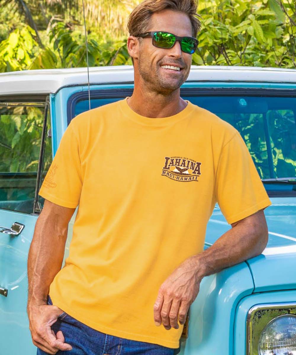 A man wearing a yellow short sleeve crewneck t-shirt with ' Lahaina Maui Hawaii' printed on the chest while leaning against a truck. View 3