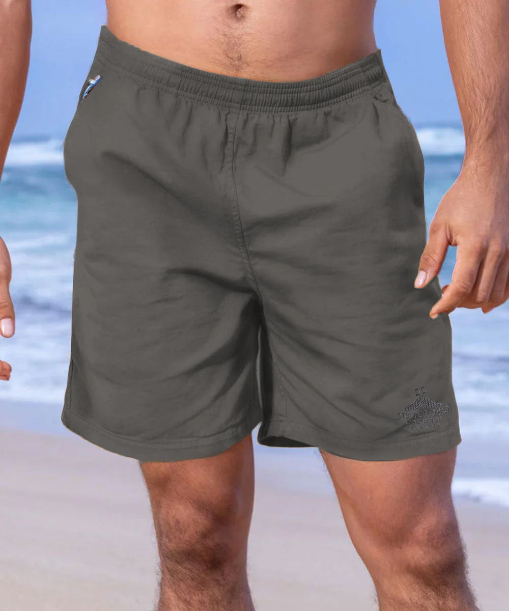 A pair of gray cotton twill shorts with an elastic waistband, deep front pockets, and a drawstring. The image features a male model wearing the shorts at a beach setting. View 2