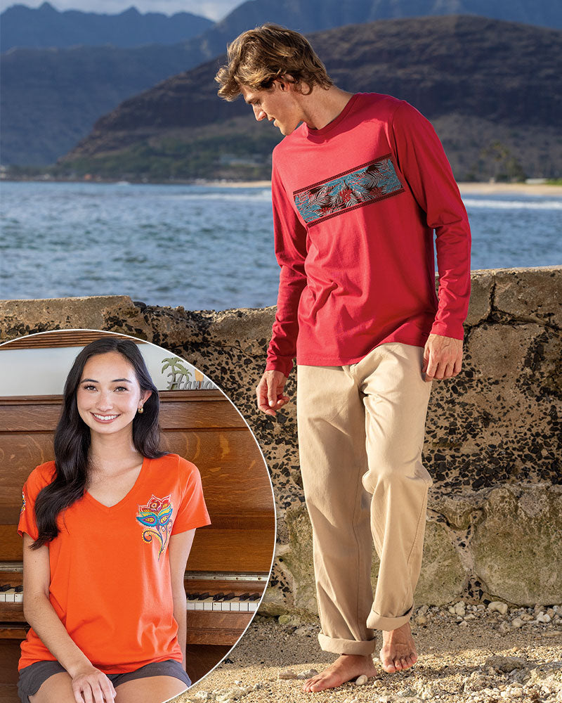 Two people wearing red and orange shirts with a mountain design, standing by a body of water.