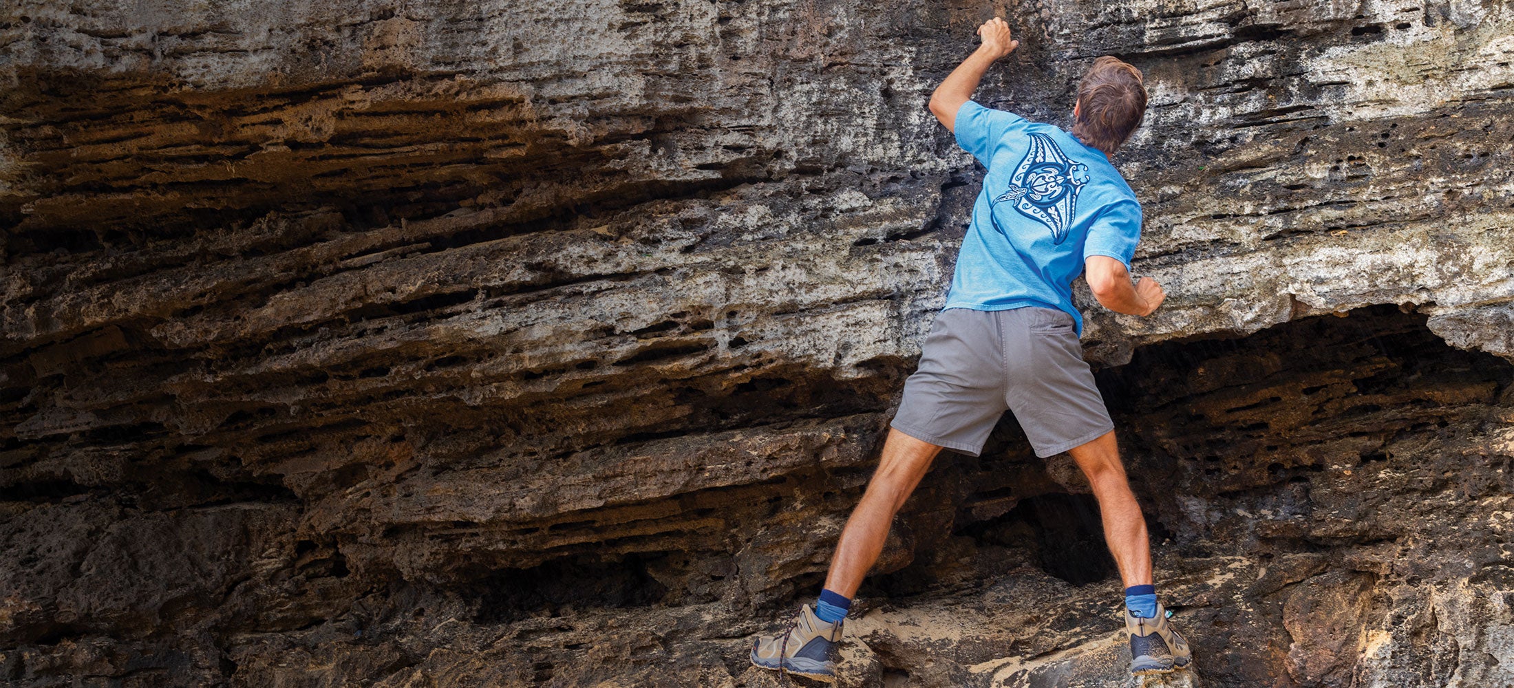 Person climbing a rocky cliff face