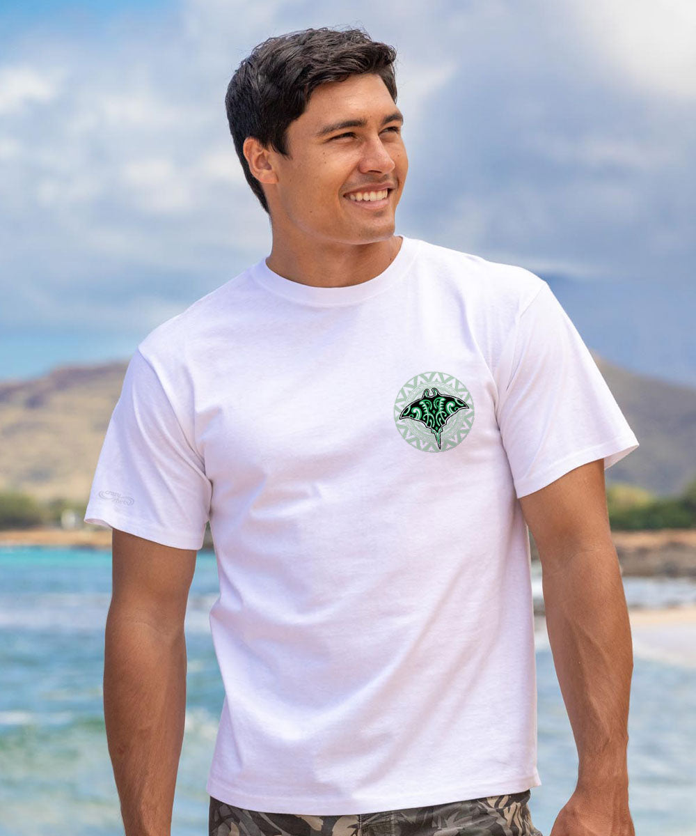 Man in white t-shirt with a small green manta ray logo with the beach in the background. View 3