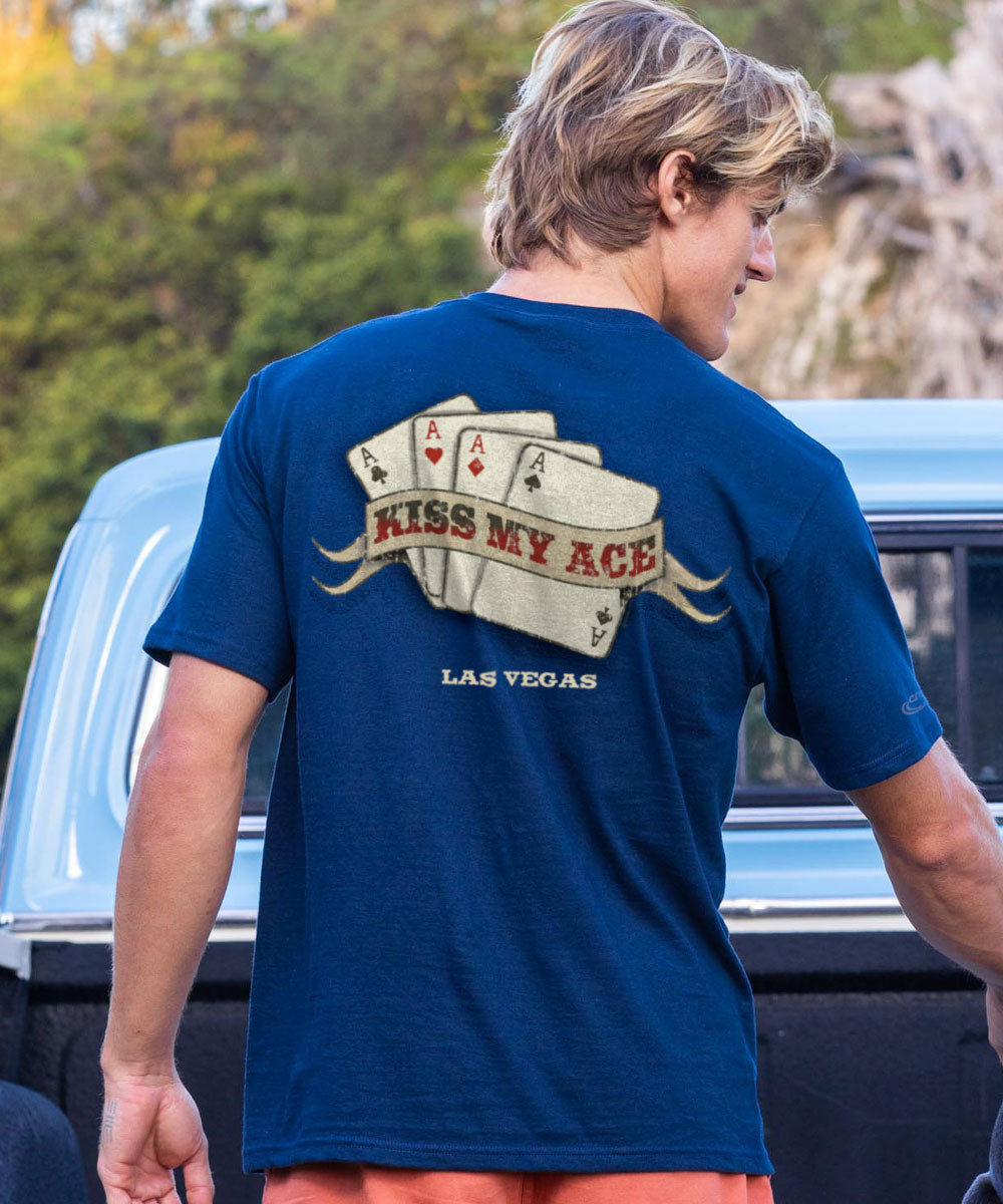 Person wearing a blue t-shirt with a graphic design and text, standing next to a truck outdoors. View 3