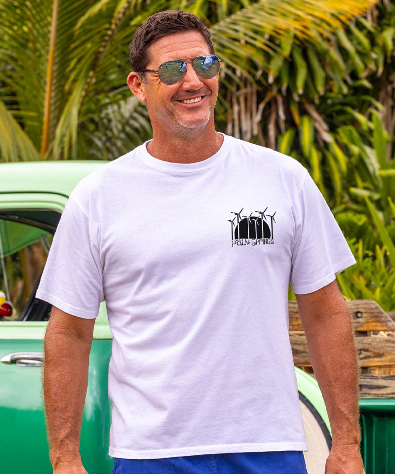 Man wearing white t-shirt with windmill pocket graphic standing in front of vintage truck View 3
