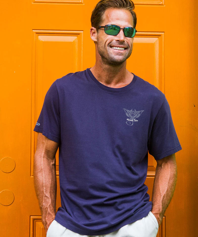 Man wearing a navy blue t-shirt with a logo in front of an orange door View 3