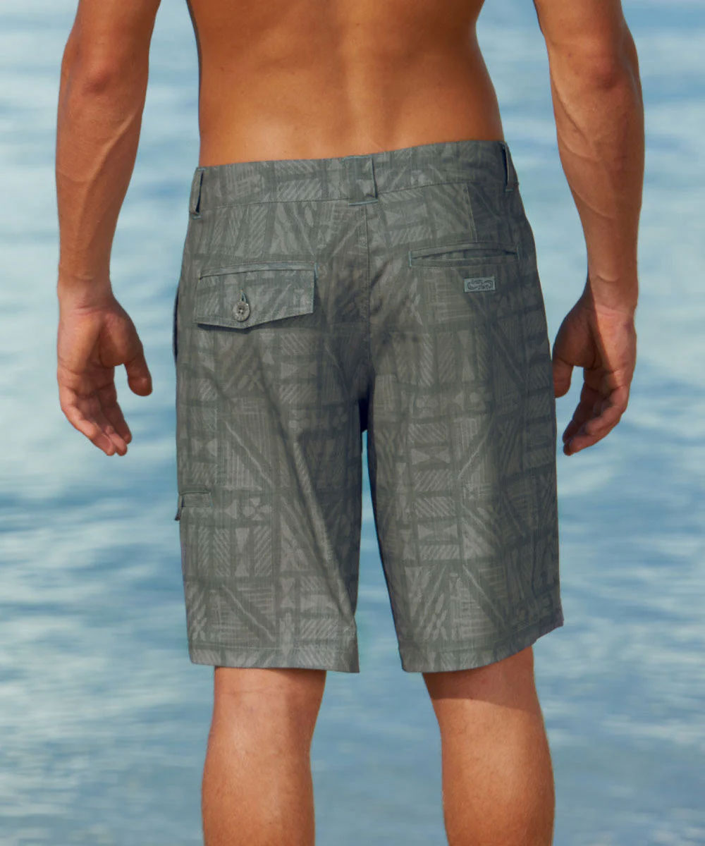 Person wearing grayish green patterned shorts standing by a body of water View 3