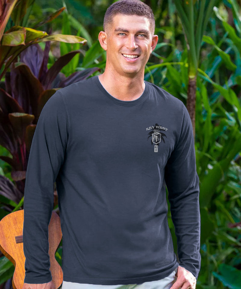 Man wearing a black long-sleeve shirt with a logo, standing outdoors with greenery in the background View 3