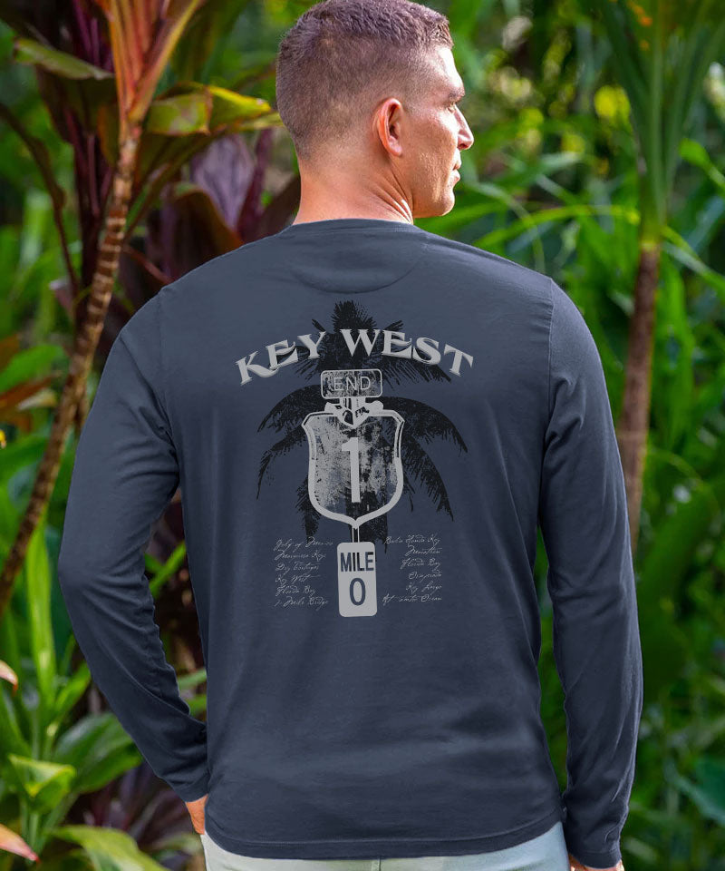 Man wearing a dark gray long-sleeve shirt with 'Key West' design in a tropical setting View 2