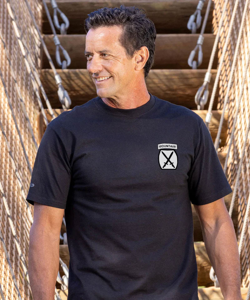 Man wearing a black t-shirt with a logo standing in front of wooden steps. View 3