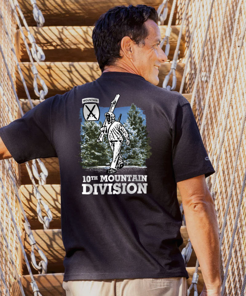 Man wearing a black t-shirt with '10th Mountain Division' graphic on the back, standing against a wooden staircase. View 2