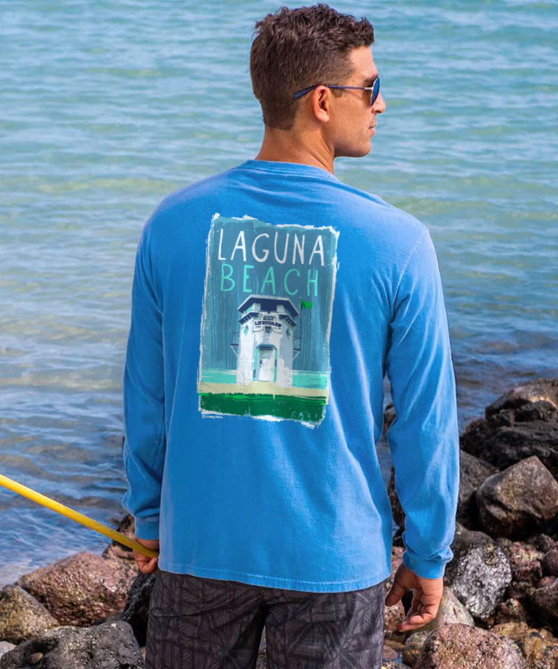 Man wearing a blue long-sleeve shirt with 'Laguna Beach' text by the water. View 2