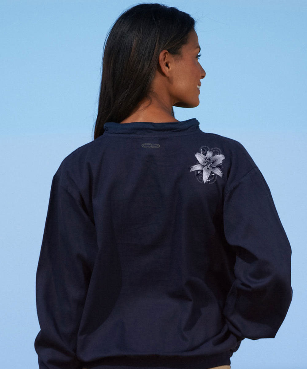 woman standing outdoors wearing a navy long sleeve lightweight pullover with a white floral design. View 3