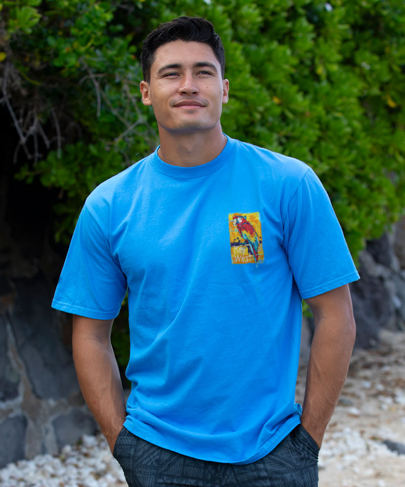 Man wearing a blue t-shirt with a colorful parrot graphic on a natural background View 3