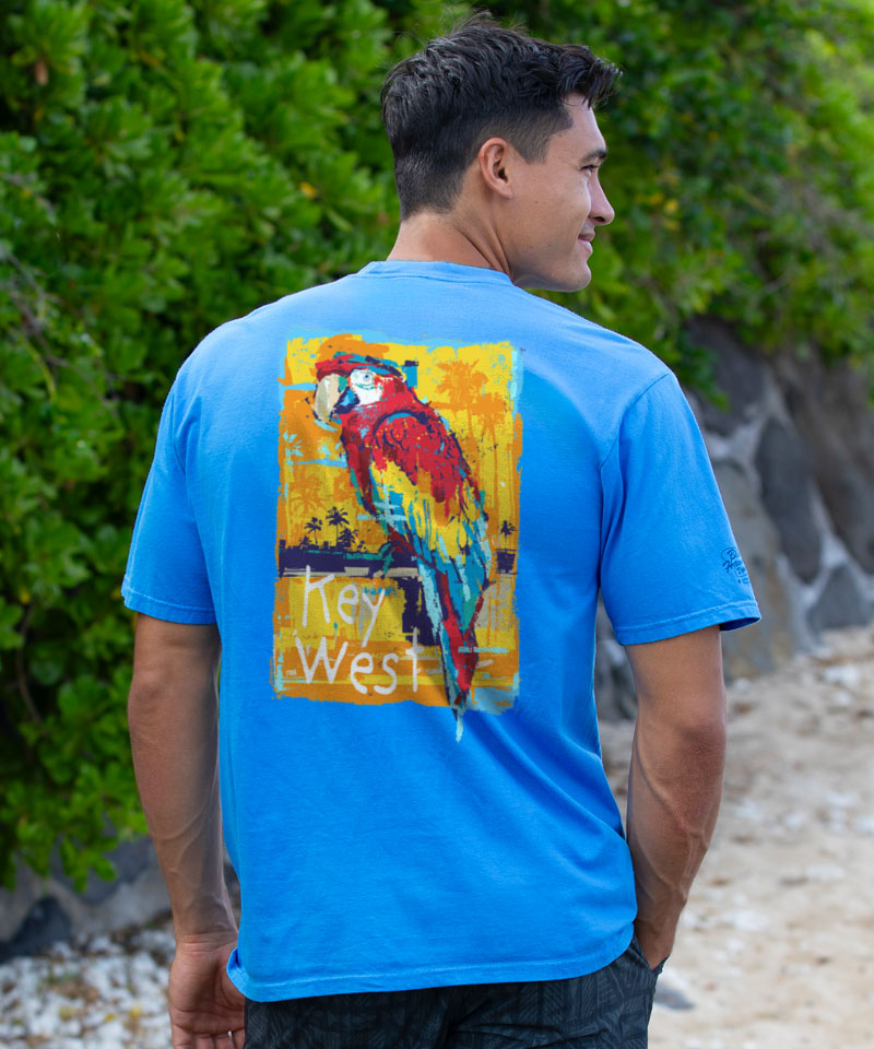 Man wearing blue t-shirt with a parrot design standing in front of greenery View 2