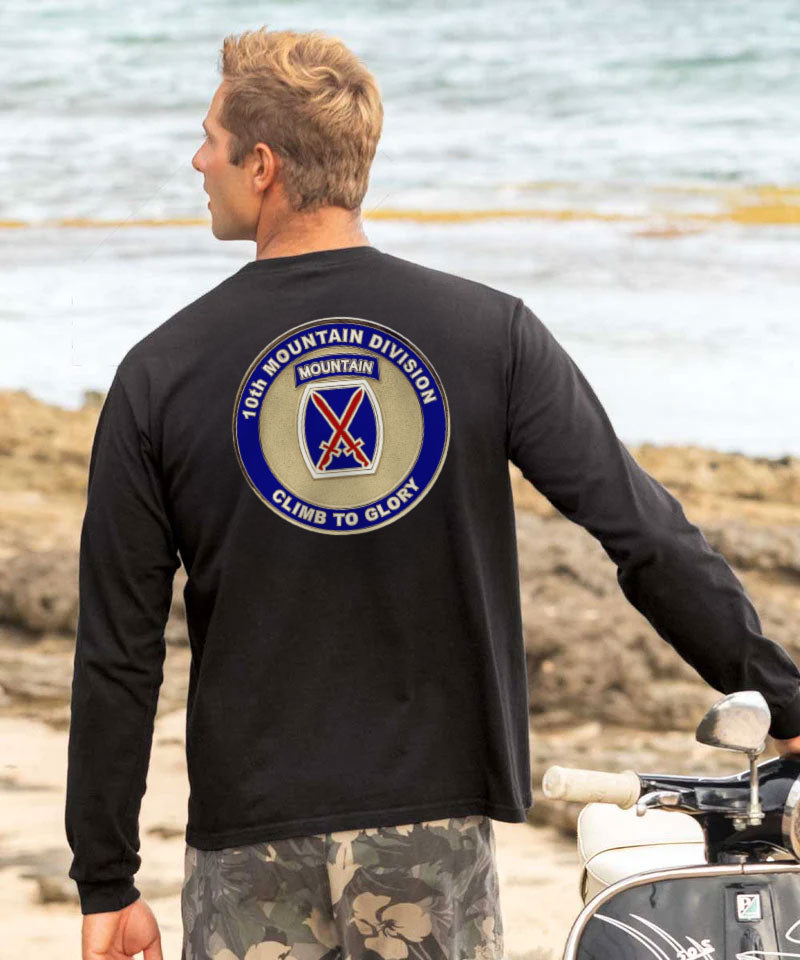 Man wearing a black long-sleeve shirt with a military emblem on the back, standing by a body of water. View 2
