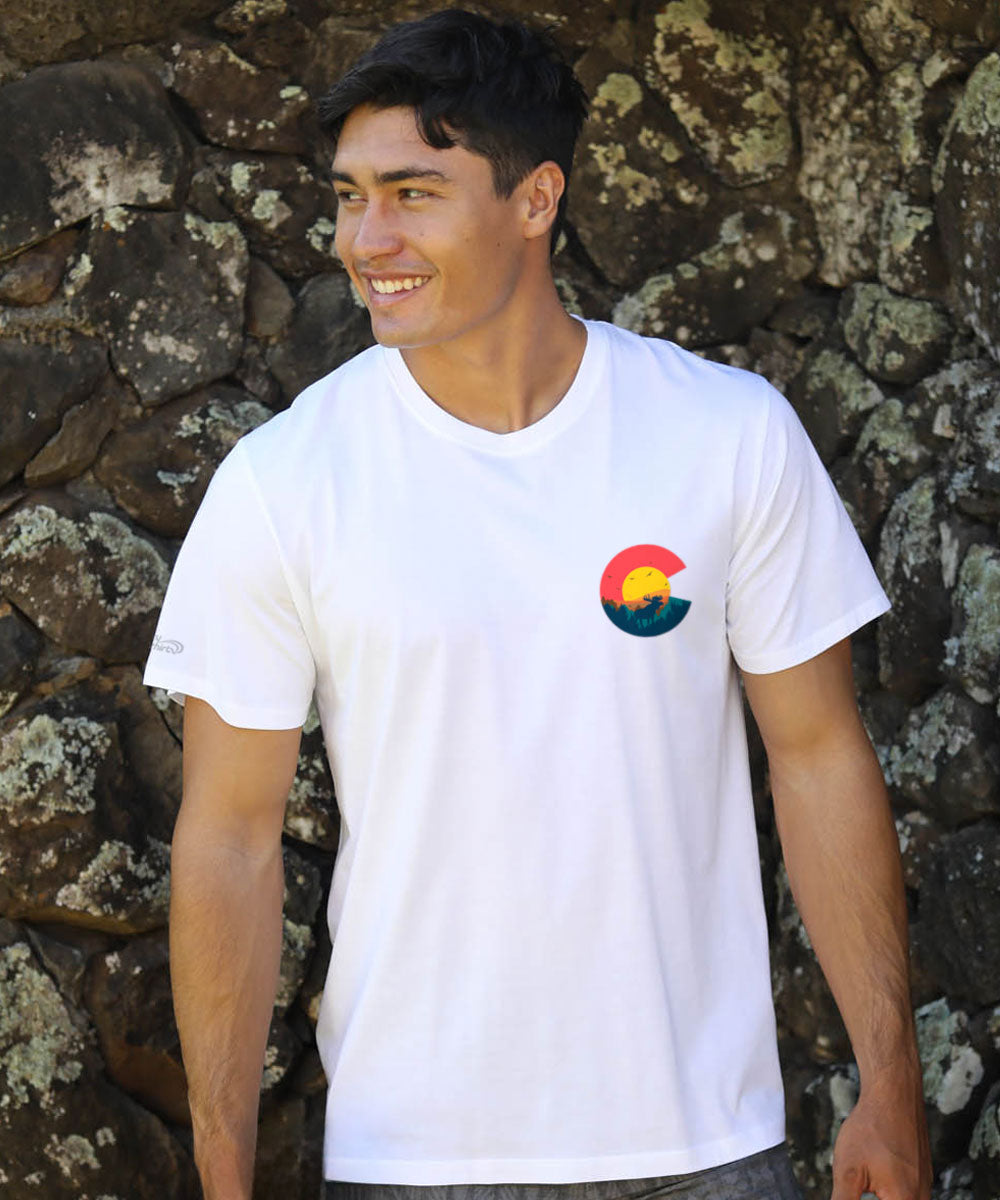 Man wearing a white t-shirt with a colorful logo against a stone wall. View 3