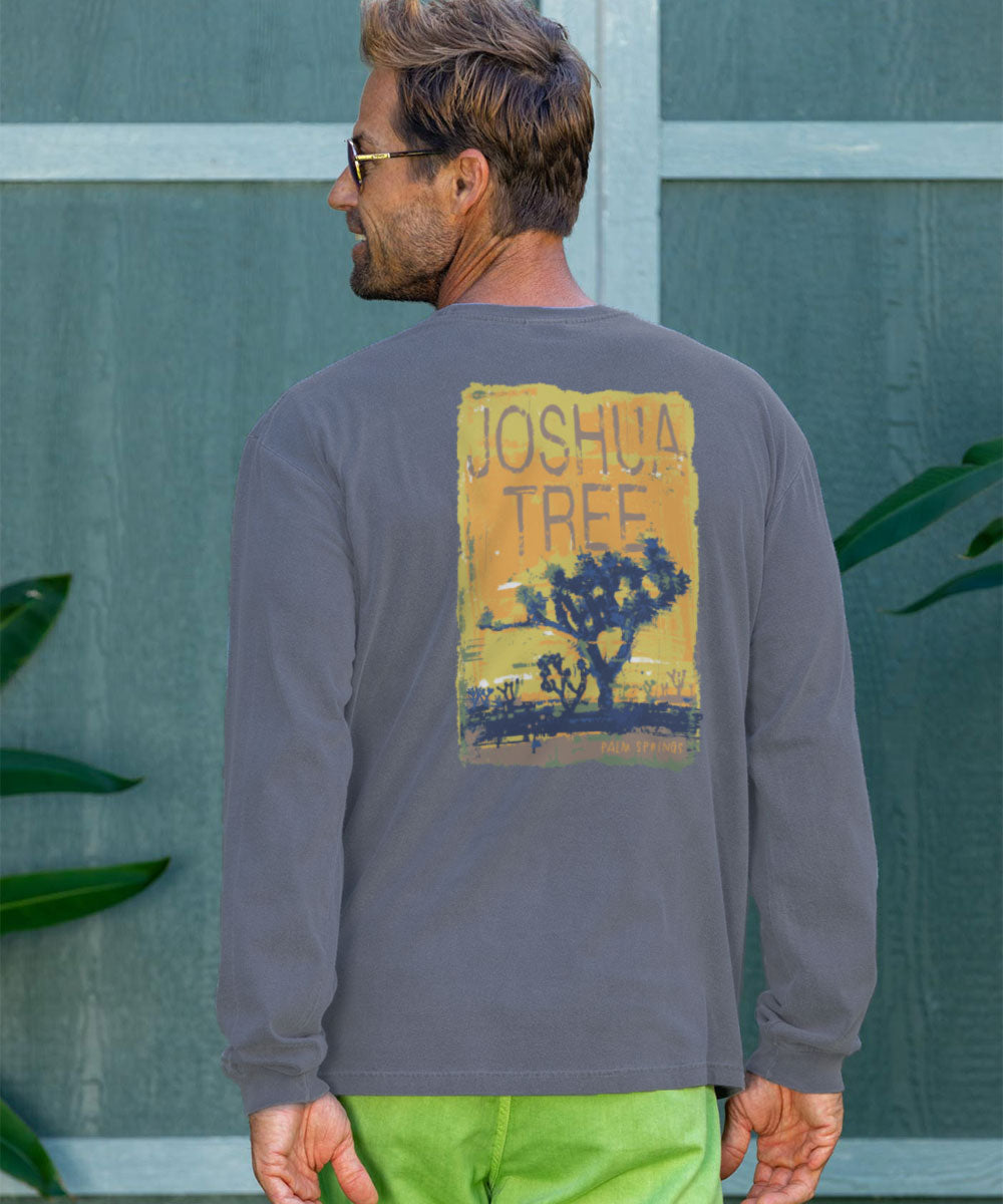 Man wearing a long-sleeve shirt with 'Joshua Tree' graphic on the back, standing against a green wall. View 2