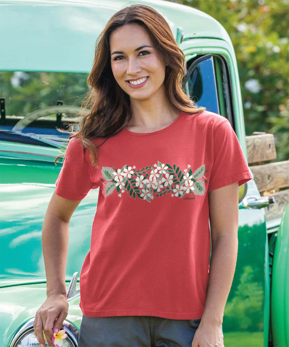 Woman wearing a red t-shirt with floral design in front of a green truck. View 2