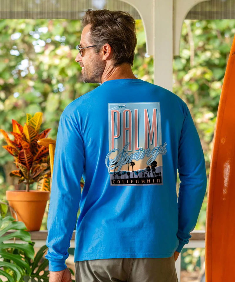 Man wearing a blue long-sleeve shirt with 'Palm Springs California' design outdoors. View 2