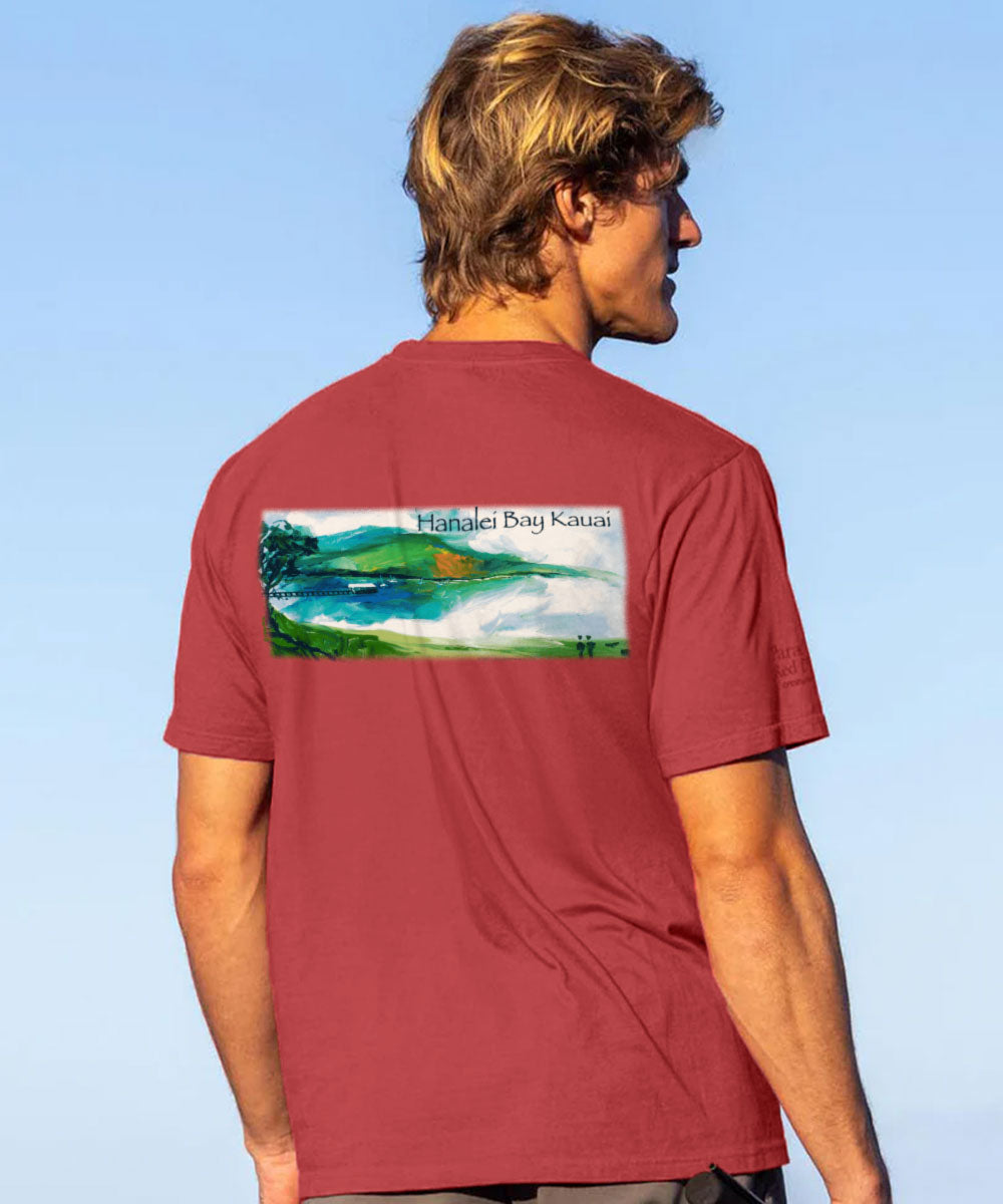 Man wearing a Red t-shirt with a scenic graphic on the back, standing against a brown wall. View 2