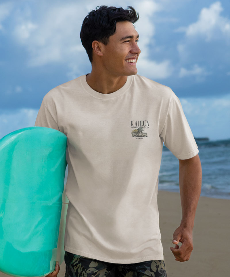 Man holding a teal surfboard on a beach with a Kailua shirt View 3