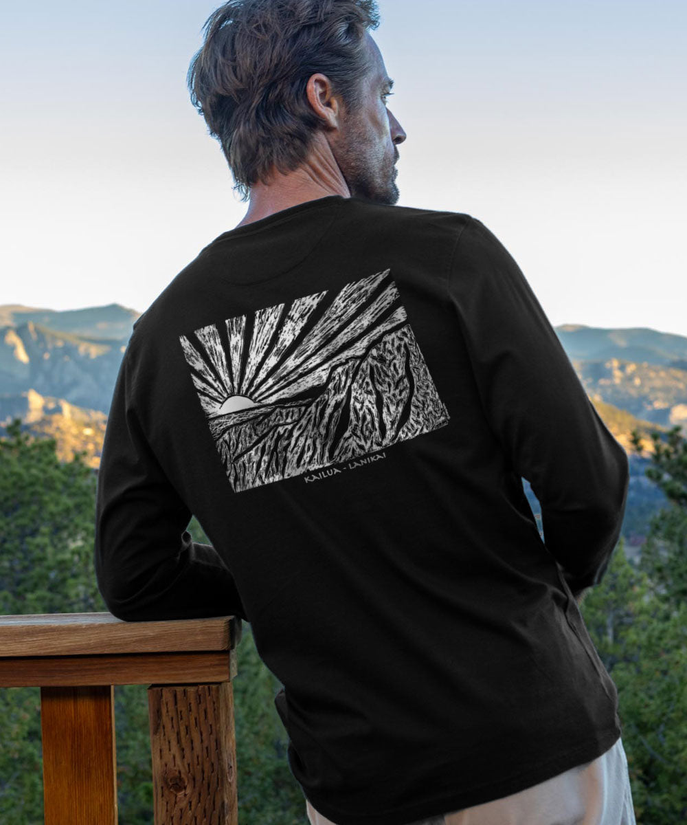 Man wearing a black long-sleeve shirt with a mountain graphic on the back, standing in a scenic outdoor setting. View 2
