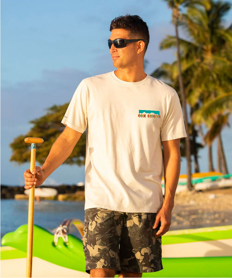 Man holding a paddle on a beach with palm trees in the background View 3
