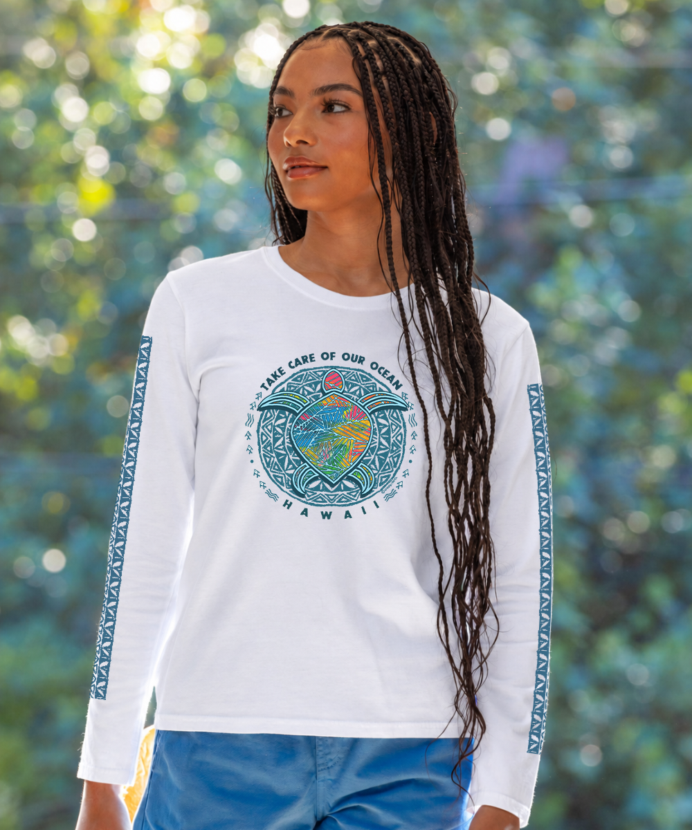 A woman with long black braids wearing a white long-sleeve t-shirt with a blue and multicolor 'Take Care of Our Ocean' graphic on the chest and patterned blue sleeve bands, set against a blurred green bokeh background. View 2