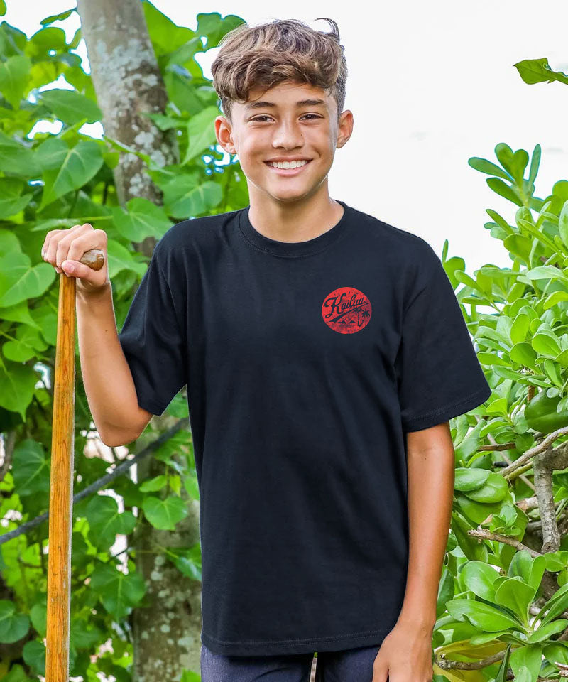 A young boy wearing a black t-shirt with a red logo outdoors View 3