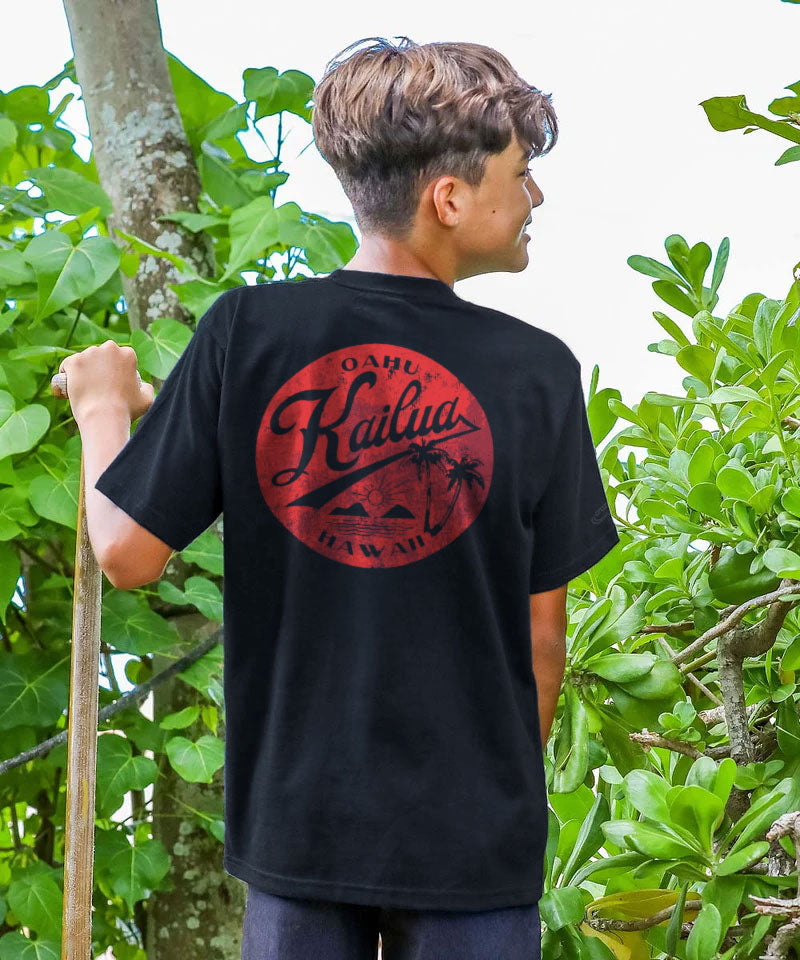 A young boy wearing a black t-shirt with a red logo in a natural setting View 2