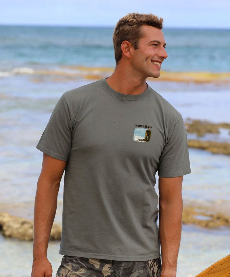 Man wearing a gray t-shirt with a small graphic on a beach View 3