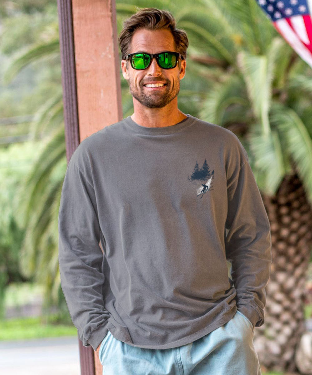 Man wearing a gray long-sleeve shirt with a logo, sunglasses, and light blue jeans outdoors. View 3