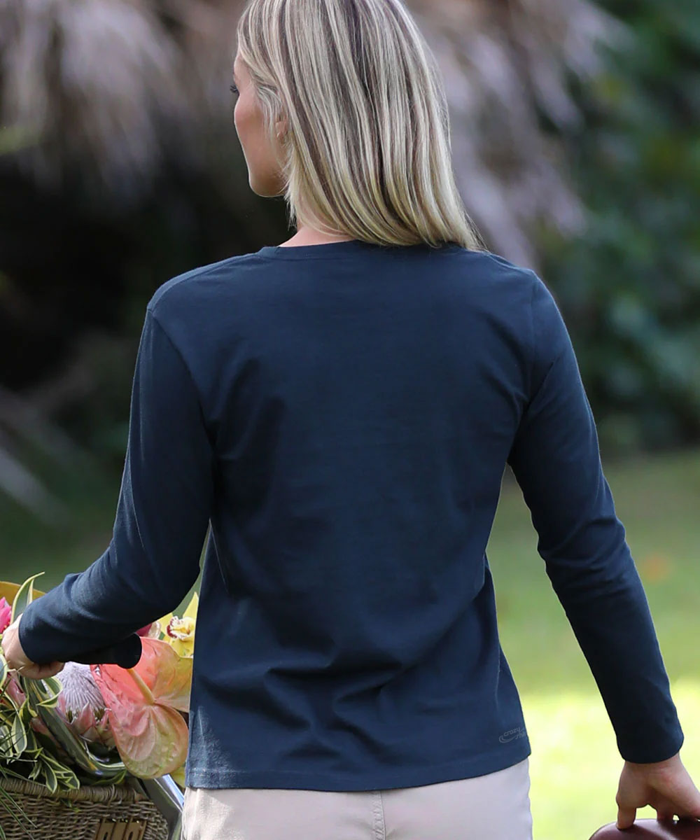 Woman wearing a navy long-sleeve shirt holding a basket of flowers outdoors. View 3