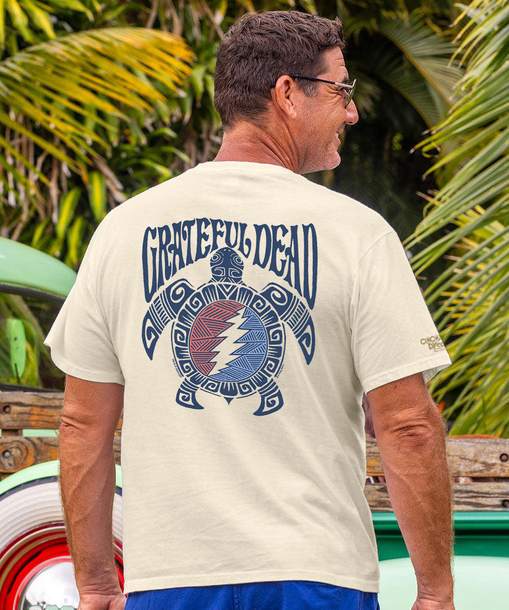 Man wearing a 'Grateful Dead' t-shirt with a turtle design, standing in front of a vintage truck and palm trees. View 2
