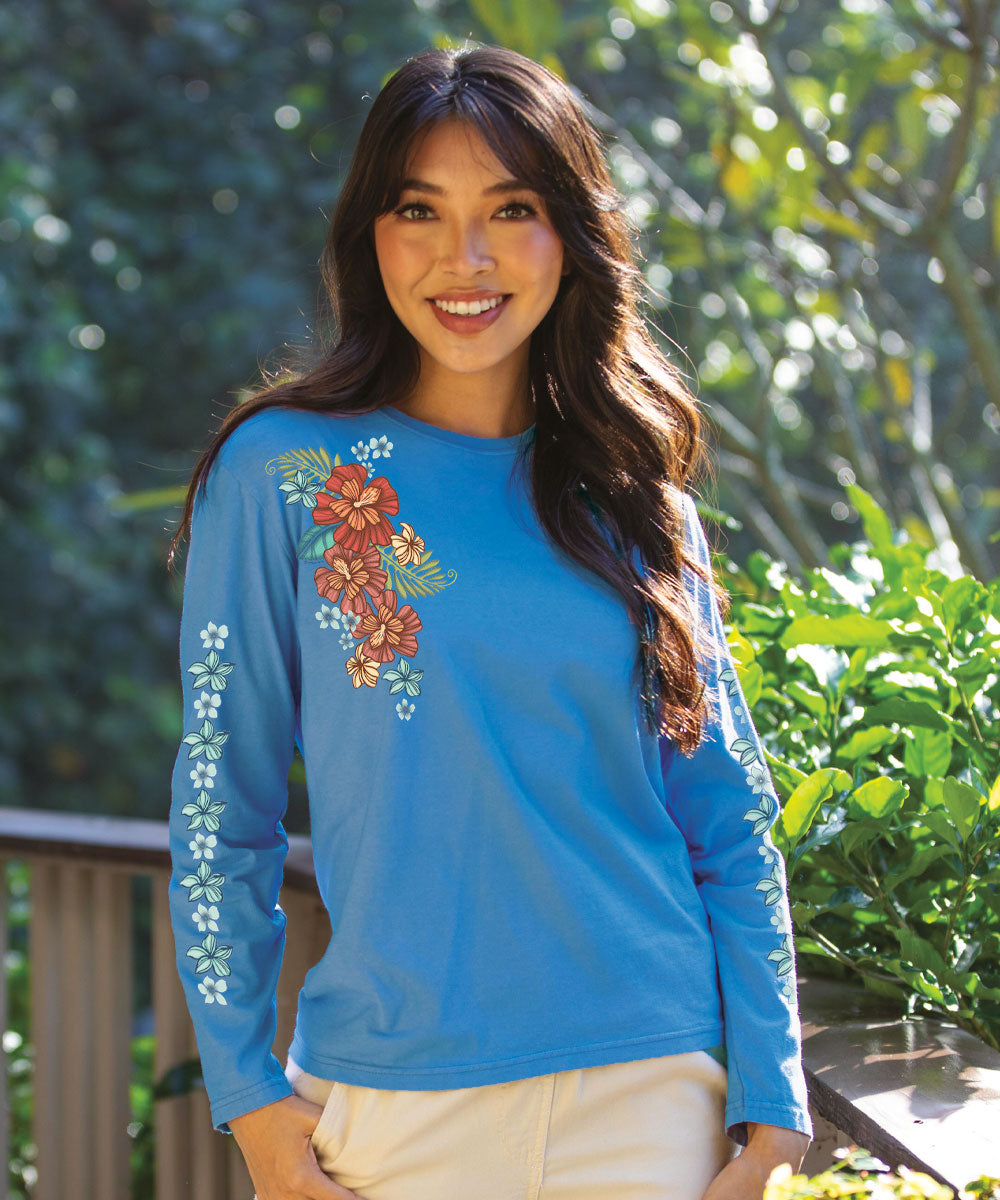 A woman wearing a blue long-sleeve crewneck t-shirt with a floral design in a garden setting.