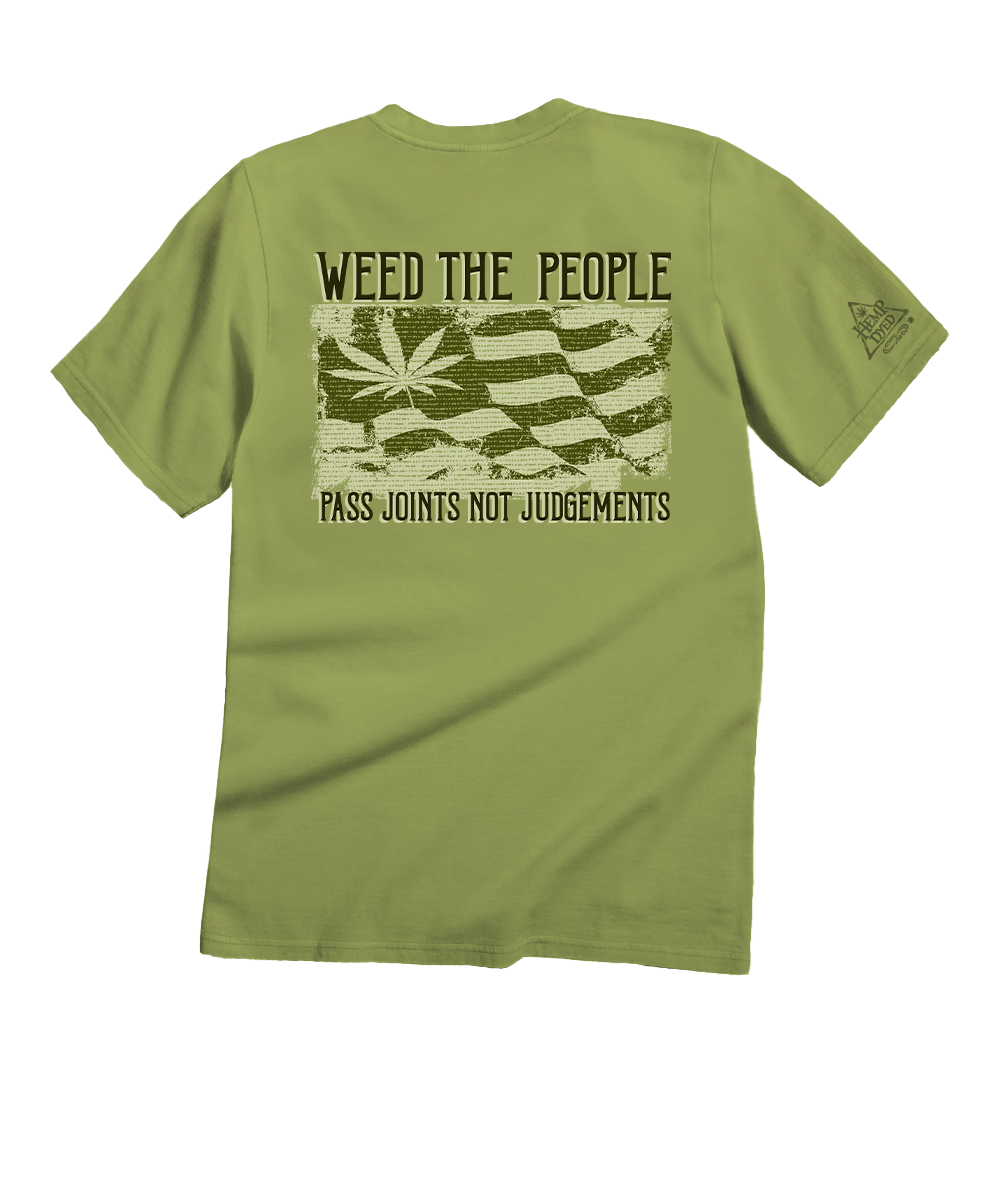 An olive green short-sleeve t-shirt shown from the back, featuring a distressed graphic of a cannabis leaf over a striped flag and the text 'WEED THE PEOPLE' and 'PASS JOINTS NOT JUDGEMENTS'. View 1
