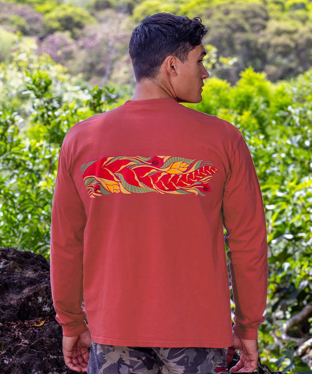 Person wearing a red long-sleeve shirt with a colorful design on the back, standing in a natural setting. View 3