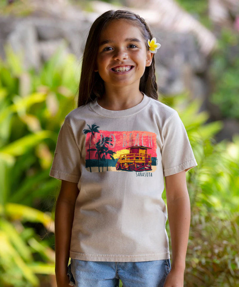 Young girl wearing a t-shirt with a colorful graphic design outdoors. View 2