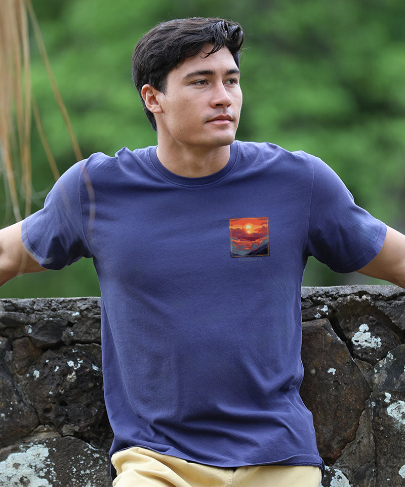 Man wearing an indigo t-shirt with a small logo standing against a wall View 2