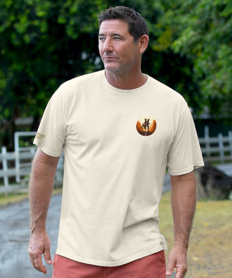 Man wearing a creamy white t-shirt with a logo, standing outdoors View 3
