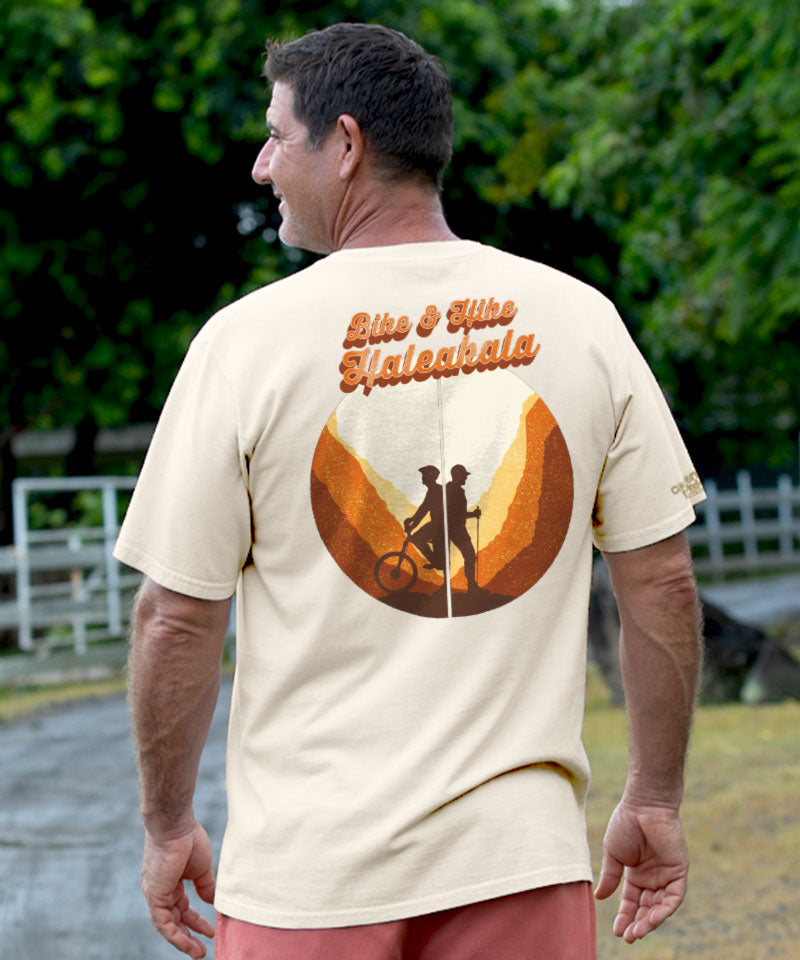 Man wearing a creamy white t-shirt with a graphic design on the back, standing outdoors. View 2