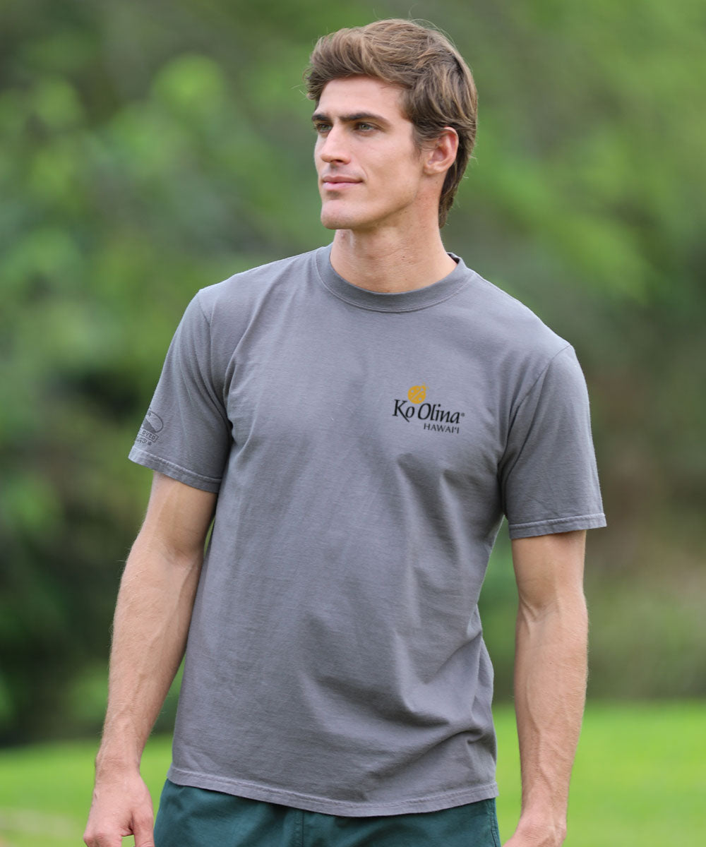 Man wearing a gray t-shirt with a logo, standing outdoors View 3