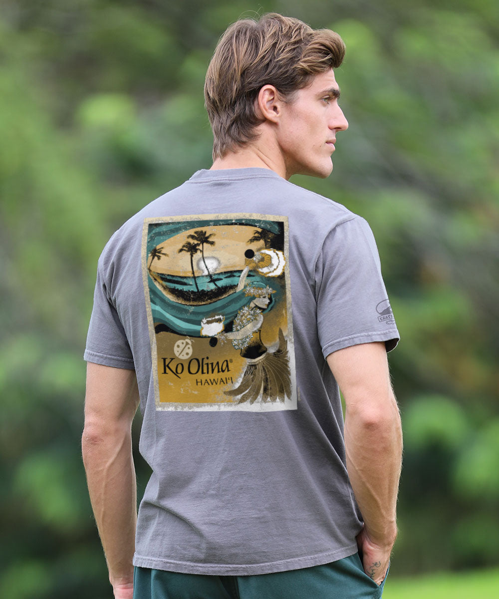 Man wearing a gray t-shirt with a graphic design on the back, standing outdoors with greenery in the background. View 2